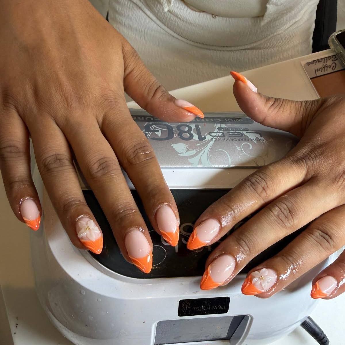 Oranje french, de hand onder de nagellamp in de studio